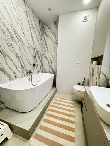a white bathroom with a tub and a sink at 4х комнатная Премиум класс возле Хан шатыра in Astana