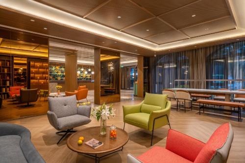 a lobby with colorful chairs and a table at Orange Sanhe Yanjiao Railway Station Hotel in Gaoxinzhuang