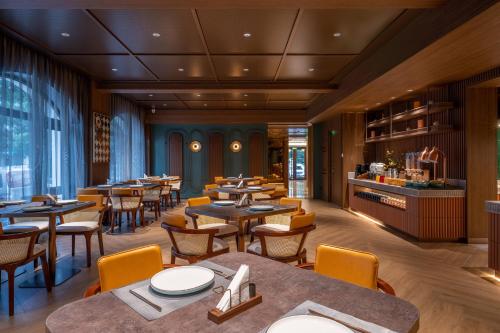 a restaurant with tables and chairs and a bar at Orange Sanhe Yanjiao Railway Station Hotel in Gaoxinzhuang