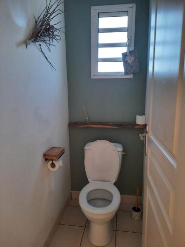 a bathroom with a white toilet with a window at Ylang Ylang in Saint-Leu