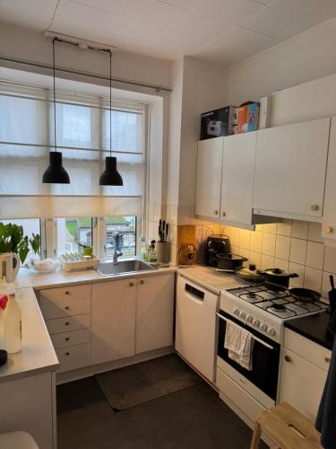 a kitchen with white cabinets and a stove top oven at Nordhavn Cozy Room in shared apartment in Copenhagen