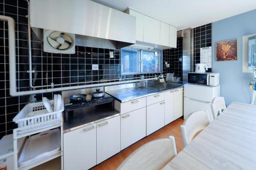 a kitchen with white cabinets and black tiles on the walls at Grace Heiwajima by Tranova in Tokyo
