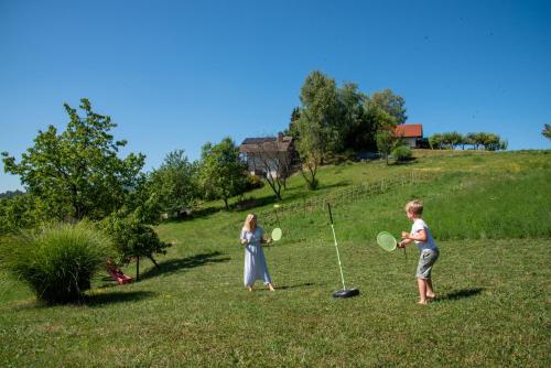 two children playing with tennis rackets in a field at Martin's Family Cottage with Hot Tub & Views in Šmarje pri Jelšah