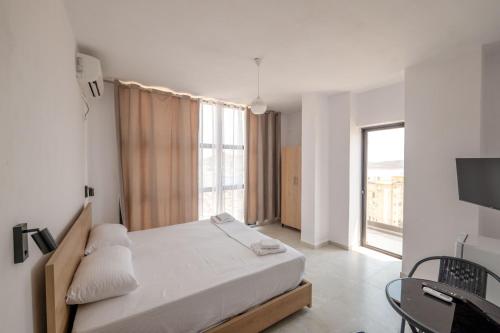 une chambre avec un lit et une grande fenêtre dans l'établissement Brian's Rooms, à Saranda