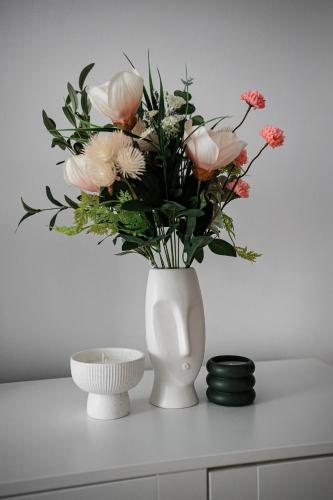 a white vase with flowers in it on a table at Forest Edge Retreat in Lupeni