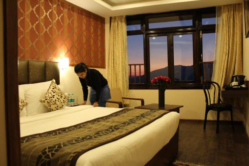 a woman standing next to a bed in a hotel room at Hotel Orchid in Gangtok