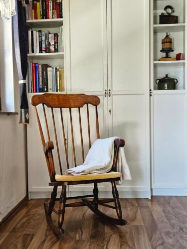 a wooden rocking chair in a room with a book shelf at Martin's Family Cottage with Hot Tub & Views in Šmarje pri Jelšah