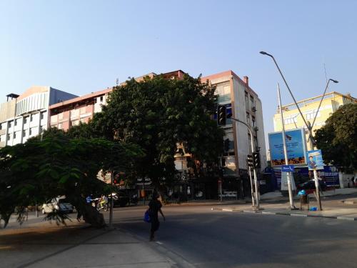 a person walking across a street next to a tree at Westend renting 2 bed Sagrada Família in Luanda