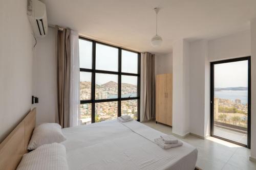 une chambre avec un lit et de grandes fenêtres dans l'établissement Brian's Rooms, à Saranda