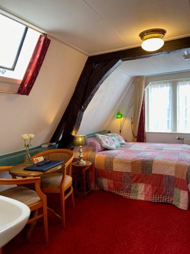 a bedroom with a bed and a table and a sink at Hotel & Restaurant De Fortuna in Edam