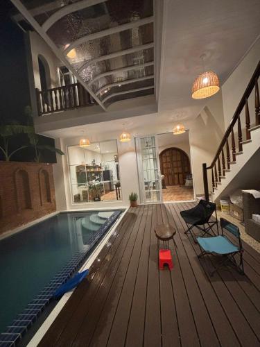 a house with a swimming pool with a table and chairs at à Bleu Hoian in Tân Thành (1)
