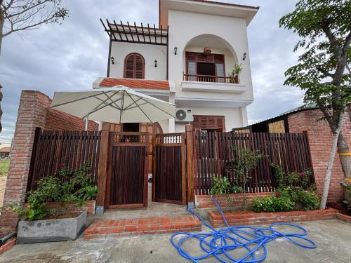 a house with a fence and an umbrella at à Bleu Hoian in Tân Thành (1)