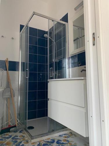 a glass shower in a bathroom with blue tiles at Casa di Eleonora in Ventotene