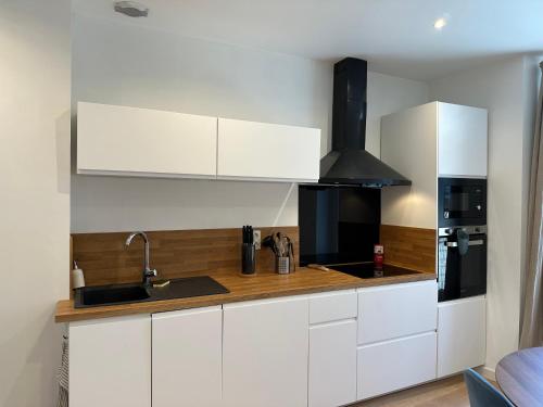 een keuken met witte kasten en een fornuis bij Appartement entier Cosy in Grenoble