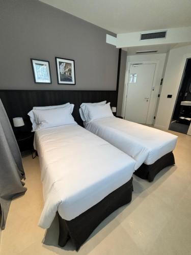 two beds in a hotel room with white sheets at Hotel Stelvio Tirano in Tirano