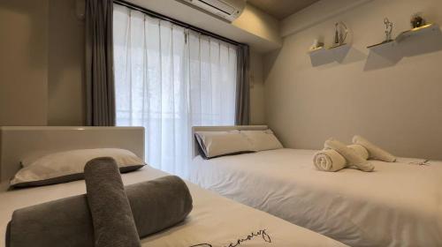 ein Schlafzimmer mit zwei Betten und einem Fenster in der Unterkunft Kumo 云 in Osaka