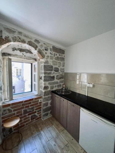 eine Küche mit einer Backsteinwand und einem Fenster in der Unterkunft sar 3 in Kotor