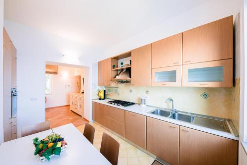 a kitchen with wooden cabinets and a table and a sink at Smeraldo Holiday House in Conca dei Marini