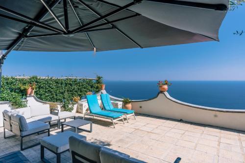 a patio with blue and white chairs and an umbrella at Smeraldo Holiday House in Conca dei Marini