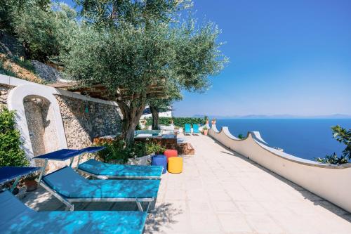 a resort patio with blue chairs and the water at Smeraldo Holiday House in Conca dei Marini