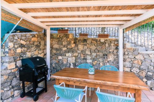a wooden table and chairs on a patio with a grill at Smeraldo Holiday House in Conca dei Marini