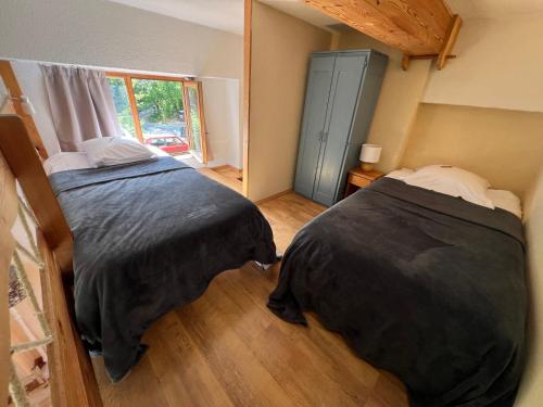 a bedroom with two beds and a window at Hôtel Restaurant Gîtes Les 5 Saisons in Freissinieres