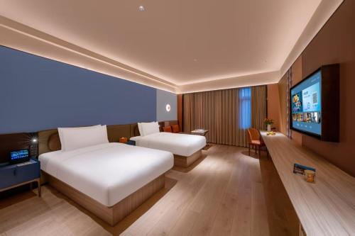 a hotel room with a bed and a flat screen tv at Orange Sanhe Yanjiao Railway Station Hotel in Gaoxinzhuang