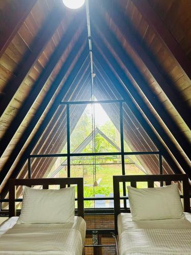 two beds in a room with a large window at Elegant Hamlets Home Stay in Chilaw