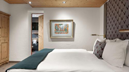 a bedroom with a white bed and a painting on the wall at Morosani Posthotel in Davos