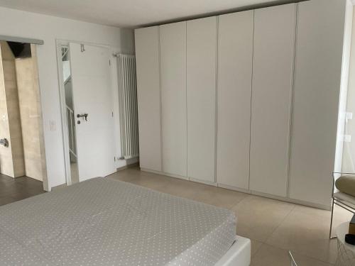 a white bedroom with a bed and a chair at Affitta camere Locarno in Minusio