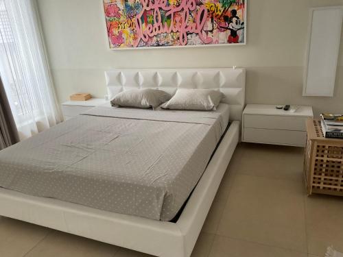 a white bed in a bedroom with a painting on the wall at Affitta camere Locarno in Minusio