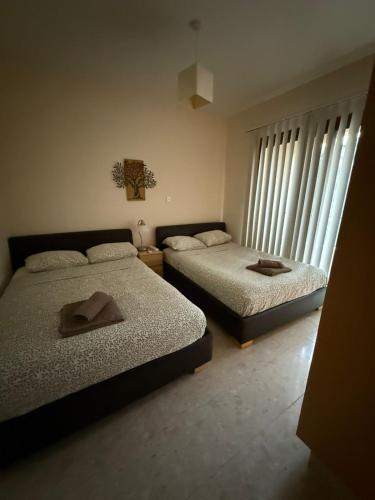 a bedroom with two beds and two windows at Modern Comfort & Sea View - Aphrodite Gardens Pissouri in Pissouri