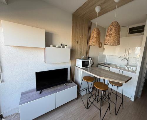une cuisine avec une table et des tabourets ainsi qu'une télévision dans l'établissement Studio Cabine Vue mer et Port, à Carnon-Plage