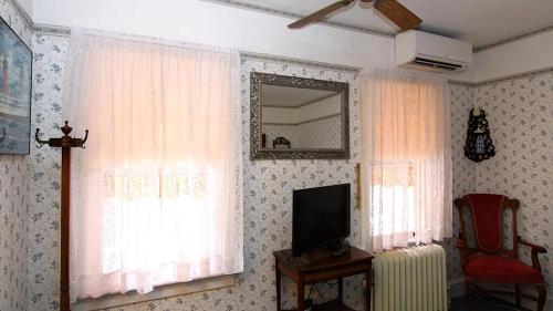 a living room with curtains and a tv and a chair at Saltwood House in Cape May