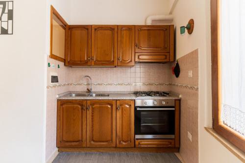 a kitchen with wooden cabinets and a stove at Da Zia Vittoria - Affitti Brevi Italia in Ulassai