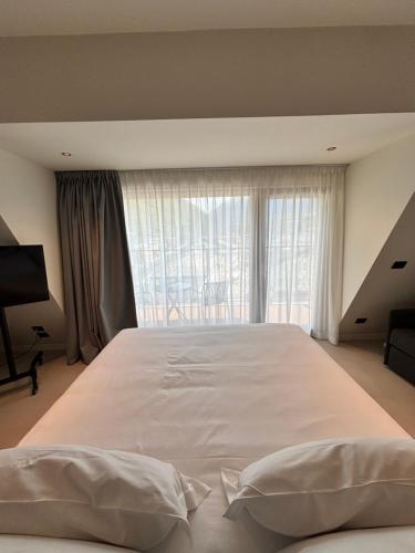 a large white bed in a room with a window at Hotel Stelvio Tirano in Tirano