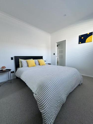 a white bedroom with a large bed with yellow pillows at Paradise Retreat in Tauranga