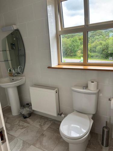 a bathroom with a toilet and a sink and a window at The Twelve Oaks in Kenmare