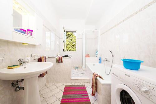 a white bathroom with a sink and a washing machine at Livingapple in Scauri