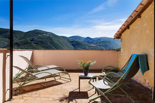 a patio with chairs and a table and mountains at Castello Di Postignano Relais in Sellano