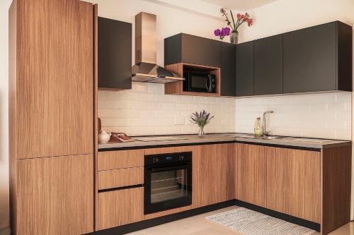 a kitchen with wooden cabinets and a stove top oven at Stylish 2-bedroom Apartment- near Valletta! Great for families or groups in Gwardamanġa
