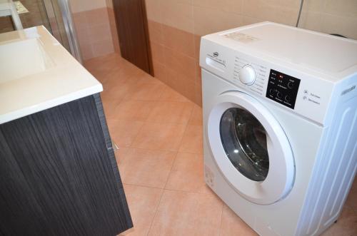 a white washing machine in a bathroom next to a counter at Top Floor Apartment 5 minutes walk to lake in Malgrate