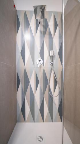 a bathroom with a shower with a geometric tile wall at Il Torrione Relais in Sirolo