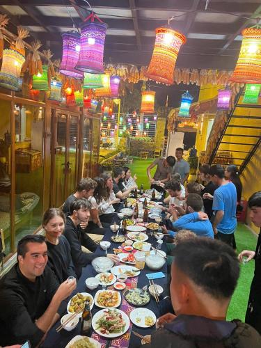 a group of people sitting at a long table eating food at Pura homestay in Yên Minh