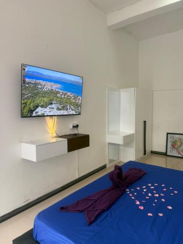 a bedroom with a blue bed and a flat screen tv at Zentara Ella by silkfive in Ella