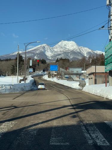 un coche conduciendo por una carretera con montañas cubiertas de nieve en Adamo Akakura, en Myoko