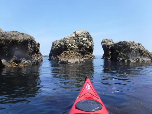 a red kayak in the water near some rocks at Ichiboukan Hanare Kai in Kyotango