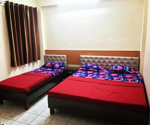 two beds in a room with red and blue pillows at SAIRATNA HOTEL only 1 minute distance from sai temple in Shirdi