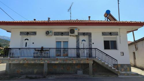 a small white house with a balcony on top at Rodostagma 1 in Rodholívos