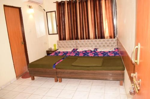 a bedroom with a large bed with a green comforter at SAIRATNA HOTEL only 1 minute distance from sai temple in Shirdi